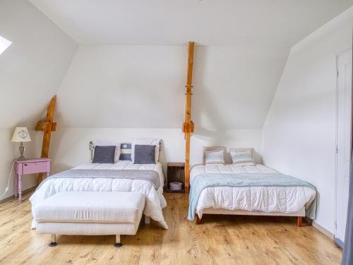 two beds in a room with white walls and wooden floors at Villa MY le Mans in Saint-Saturnin