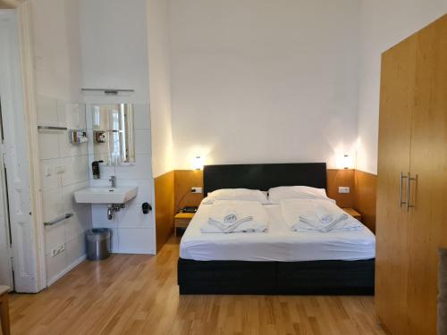 a bedroom with a bed with white sheets and a sink at Pension Ani-Falstaff in Vienna