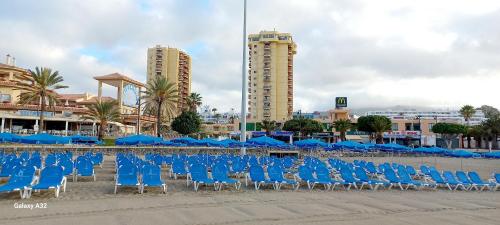 a row of blue chairs and umbrellas on a beach at SOL & MAR Playa de las vistas Torres del Sol A504 in Arona