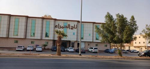 تاج الحمراء للاجنحة الفندقية Taj Al Hamra Hotel Suites في الرياض: مبنى كبير به سيارات تقف في موقف للسيارات