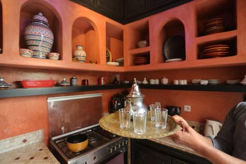 una persona che tiene un vassoio di bicchieri su un bancone in cucina di Riad En exclusivité a 99 euros avec 5 chambres a Marrakech