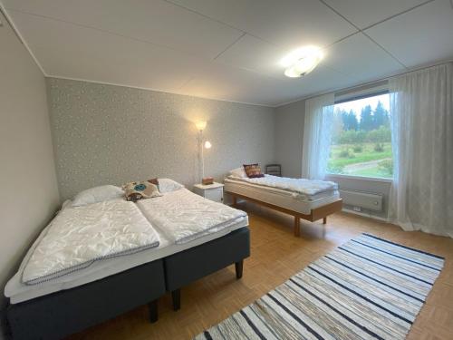 a bedroom with two beds and a window at Mäki-mummola in Ylitornio