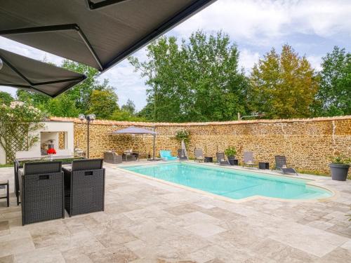 a swimming pool in a yard with a brick wall at Villa MY le Mans in Saint-Saturnin