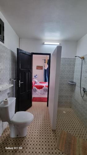 a bathroom with a toilet and a room with a bed at Villa Les Pieux in Somone