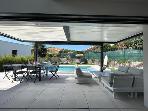 un patio avec une table et des chaises et une piscine dans l'établissement VILLA Grain De Sable PROCHE PLAGE, GOLF AVEC PISCINE, à Moliets-et-Maa