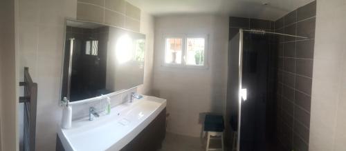 une salle de bain avec un lavabo et un miroir dans l'établissement VILLA LA PAVOTTE 4* 11 PERSONNES.PISCINE CHAUFFEE.JACCUZY OPTION., à Mimizan