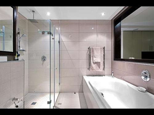 a bathroom with a tub and a glass shower at The Crystal 203 Camps bay - back-up power in Cape Town