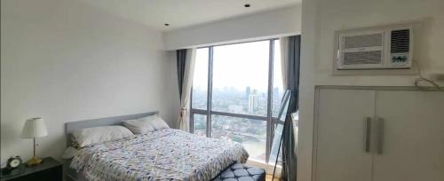 a bedroom with a bed and a large window at Modern and Comfortable Staycation - Unit 3718 Novotel Tower in Manila