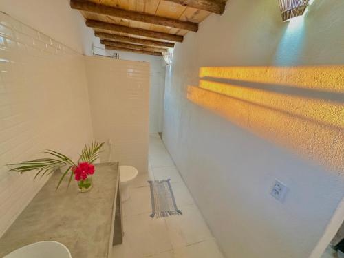 a room with a table with a red flower on it at Pousada Casa Eco Paracuru in Paracuru