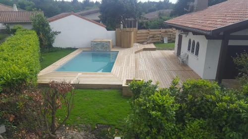 a backyard with a swimming pool and a wooden deck at VILLA LA PAVOTTE 4* 11 PERSONNES.PISCINE CHAUFFEE.JACCUZY OPTION. in Mimizan