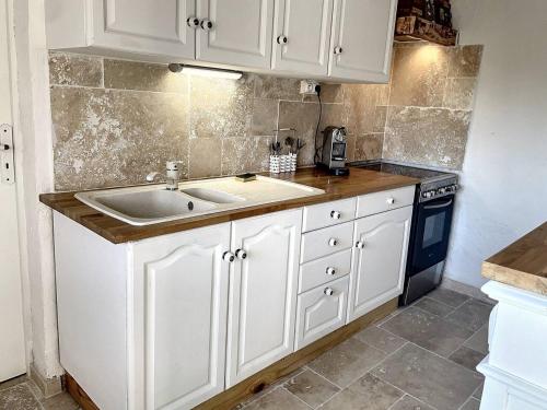 a kitchen with white cabinets and a sink and a stove at MAZET DE LORGUES in Lorgues