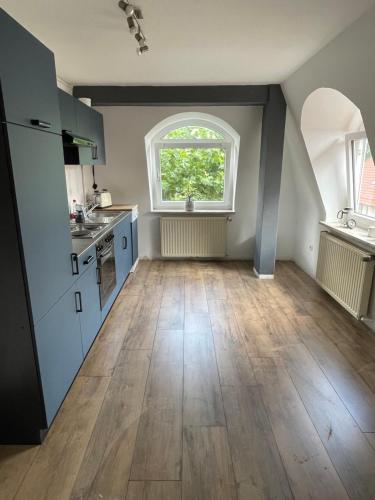 an attic kitchen with a large window and wooden floors at Im Herzen von Barsinghausen in Barsinghausen