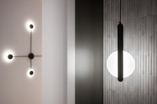 two hanging lights and a clock on a wall at Harmonia Apartament with Parking in Toruń