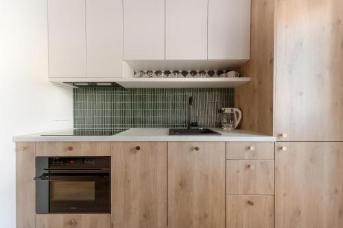 a kitchen with white cabinets and a black oven at Harmonia Apartament with Parking in Toruń