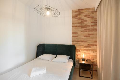 ein Schlafzimmer mit einem grünen Bett und einer Ziegelwand in der Unterkunft Harmonia Apartament with Parking in Toruń