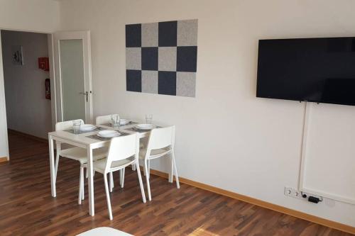 a dining room with a white table and a flat screen tv at Work & Stay 3 Room Apartment in Plettenberg