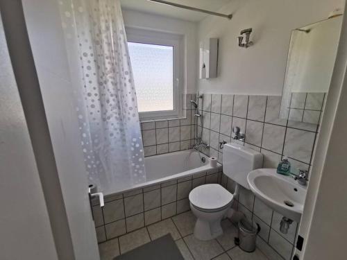 a bathroom with a toilet and a tub and a sink at Work & Stay 3 Room Apartment in Plettenberg