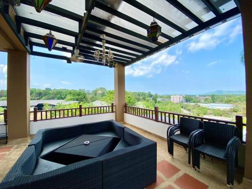 a balcony with a blue couch and chairs and a large window at Orchid Pool Villa Phuket - SHA Extra Plus in Phuket Town