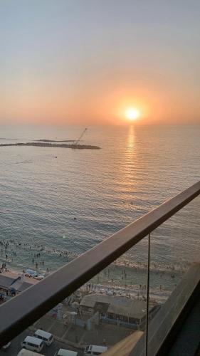 a view of the beach at sunset from a balcony at شقة فندقية فاخرة luxury apartment sea view in Alexandria