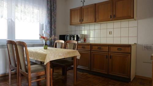 eine Küche mit einem Tisch und Stühlen sowie eine Küche mit einer Theke in der Unterkunft Gästehaus Fehrenbacher Schweiz in Masserberg