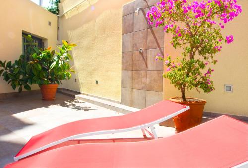 a red bench in a room with plants and flowers at Hotel Ciutat De Sant Adria in Sant Adria de Besos