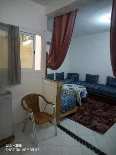 a bedroom with a bed and a chair and a window at السخينات in Es Skhinat