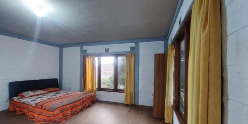 Schlafzimmer mit einem Bett und einem Fenster mit gelben Vorhängen in der Unterkunft Villa Jati in Cimandala