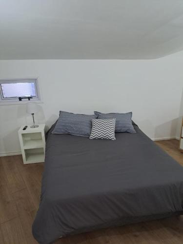 a bedroom with a large bed with a white wall at El Refugio Nuevo y cómodo depto Excelente ubicacion in San Carlos de Bariloche