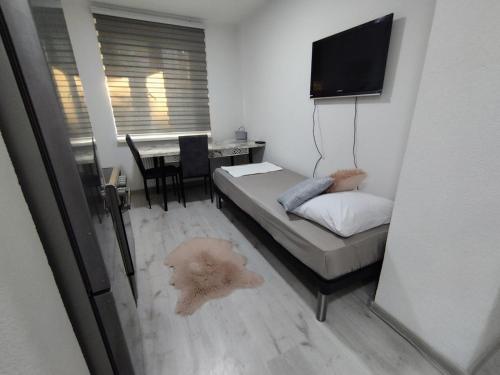 a bedroom with a bed and a table with a television at Apartment Emina in Tuzla