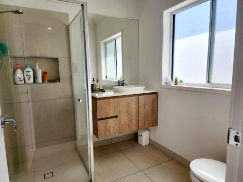 a bathroom with a shower and a sink and a toilet at Modern Luxe Retreat Brisbane in Doolandella