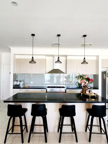 a kitchen with a large black counter with four bar stools at Modern Luxe Retreat Brisbane in Doolandella