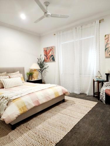 a bedroom with a bed and a ceiling fan at Modern Luxe Retreat Brisbane in Doolandella