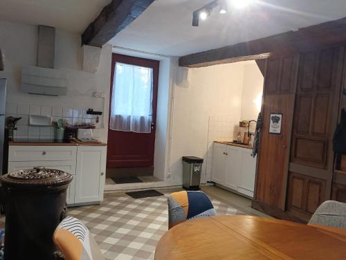 une cuisine avec une table et une porte rouge dans l'établissement Cottage reflet de bonheur, à Saint-Pierre-Bellevue