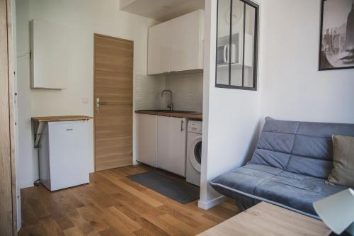 Una sala de estar con un sofá azul y una cocina. en Très beau studio 1, en Asnières-sur-Seine