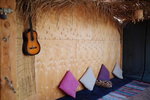 a group of pillows on a wall with a guitar at Fully equipped Remote off-grid Solar Wooden Home in Dahab