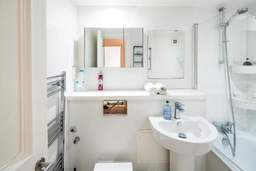 La salle de bains blanche est pourvue d'un lavabo et d'une douche. dans l'établissement Cozy 1 bedroom / Gloucester Road / Kensington, à Londres