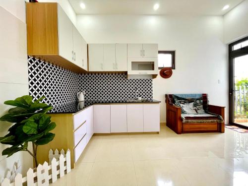 uma cozinha com armários brancos e uma parede de azulejos em preto e branco em Mini Home em Ấp Ða Lợi
