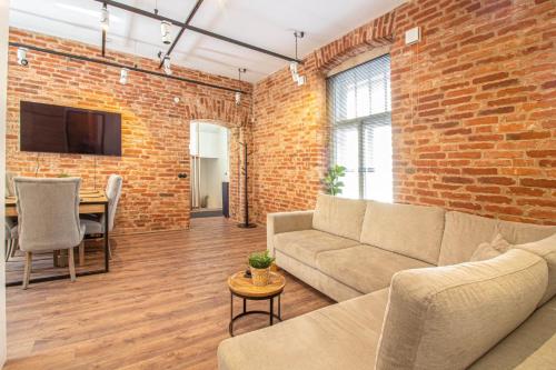 a living room with a couch and a brick wall at Old Town Luxury apartment with sauna in Tartu