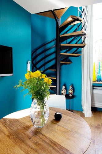 un vase avec des fleurs jaunes assis sur une table en bois dans l'établissement AJOUCADOU le nid, à Lourmarin