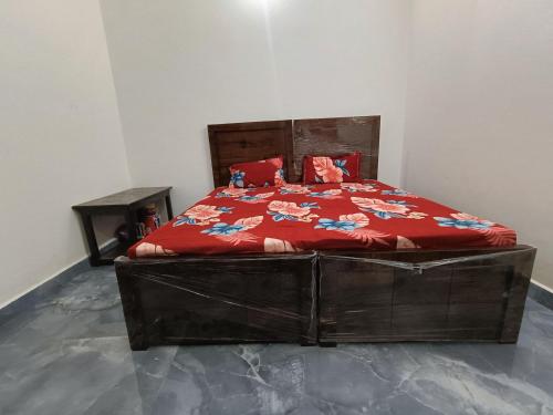 a bedroom with a bed with a red comforter at Shree Yamunaji Kripa Kunj in Gokul