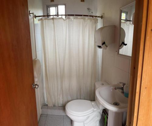 a white bathroom with a toilet and a sink at Hostel San Felipe in San Felipe