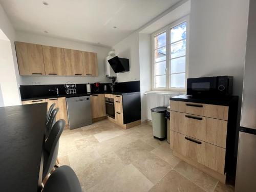 uma cozinha com armários de madeira e um balcão preto em Gite les Minimes II em Avallon