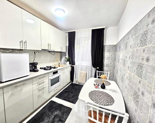 a kitchen with white cabinets and a table in it at Cazare Ploiesti in Ploieşti