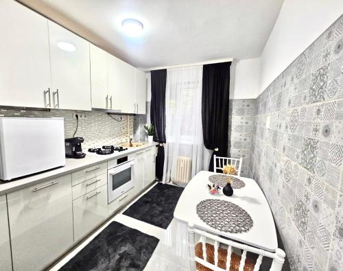 a kitchen with white cabinets and a table in it at Apartament Ploiești in Ploieşti