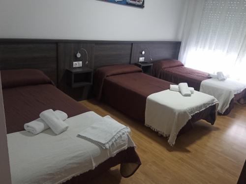 a hotel room with three beds with white sheets at Pension KM66 in Palas de Rei