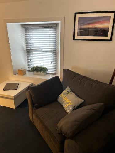 a living room with a brown couch and a window at Lochindaal Hotel in Port Charlotte