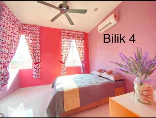 a bedroom with pink walls and a bed with a ceiling fan at Daffodil Homestay in Perlis in Kangar