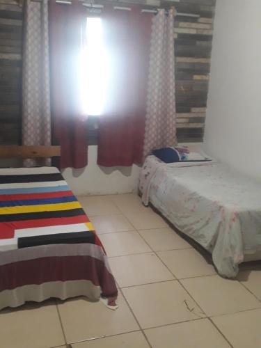 Schlafzimmer mit einem Bett und einem Fenster mit Vorhängen in der Unterkunft Casa dos corais in Vila Velha