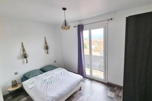 une chambre avec un lit et une grande fenêtre dans l'établissement Appartement T2 + Grande terrasse, à Perpignan