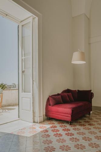 a red couch sitting in a room with a door at Relais Monastero Santa Teresa - Albergo Diffuso in Nardò